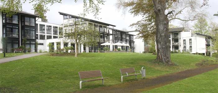 Dreigeschossiges Altenpflegeheim mit verglasten Fassaden in einem Park mit altem Baumbestand