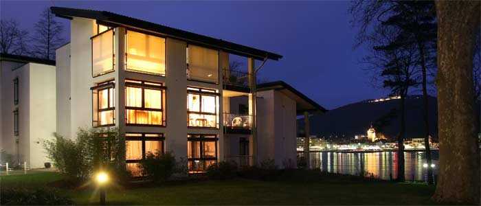 Wohnhaus am Rhein in Bonn-Mehlem bei Nacht, die verglaste Fassade warm beleuchtet