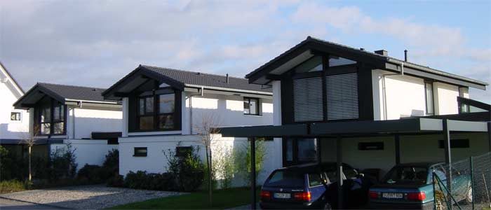 Reihe weißer Kettenhäuser mit dunklen Giebeln und Carports