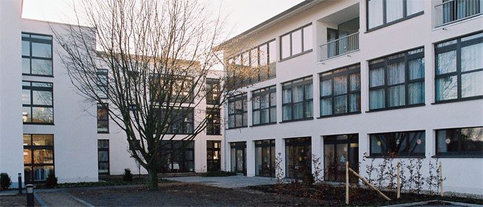 Weißer Wohnbau mit Fensterbändern und Balkonen